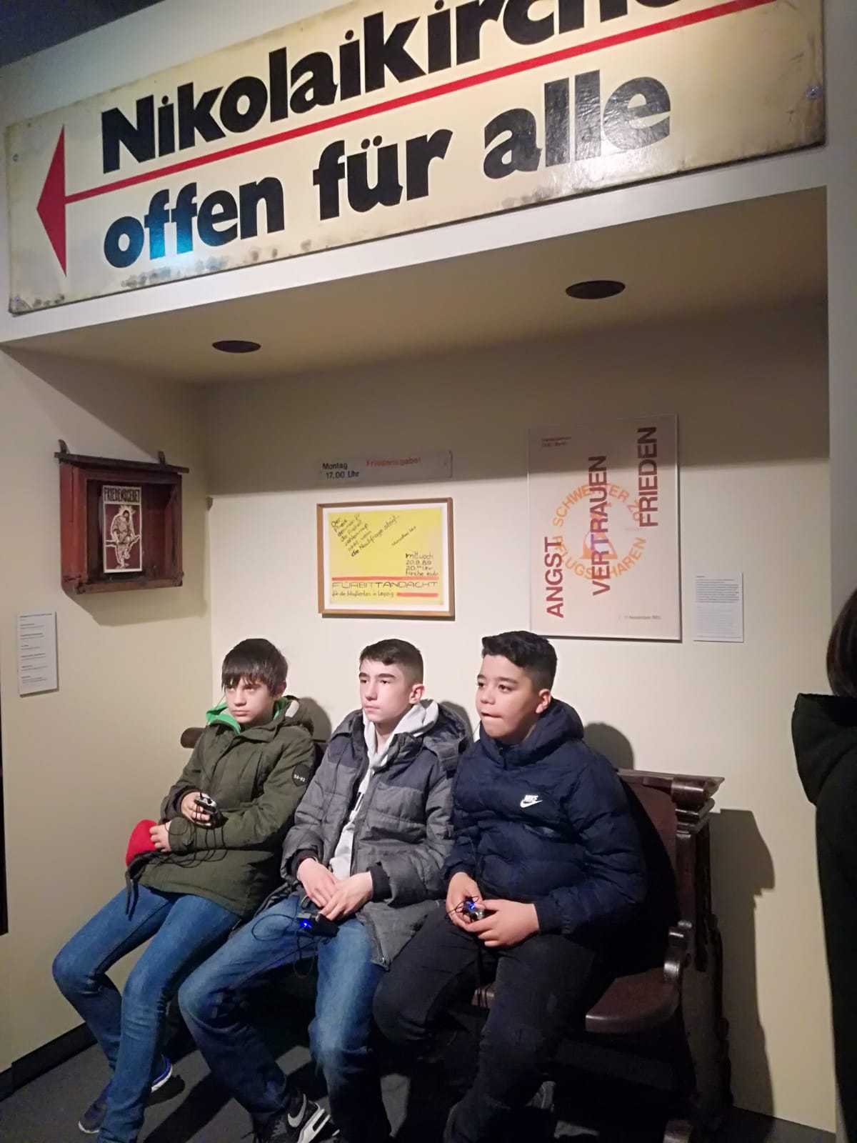 Auf diesem Bild sehen Sie drei Schüler auf einer Bank sitzen.