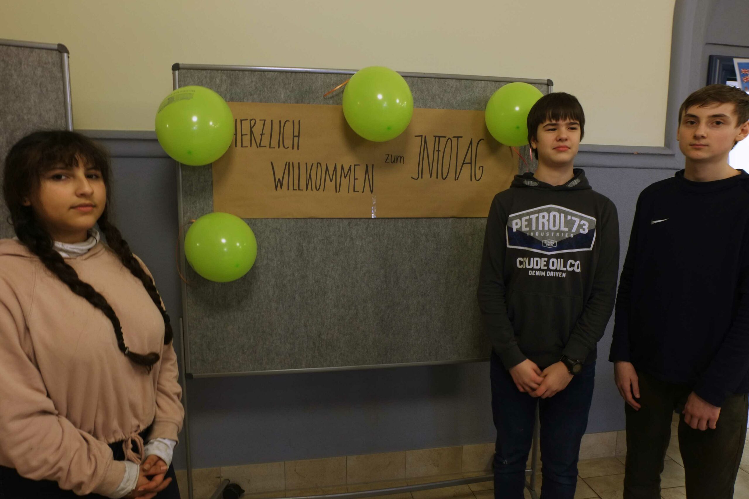 Auf diesem Bild sehen Sie Schülerinnen und Schüler vor einem Schild mit der Aufschrift 