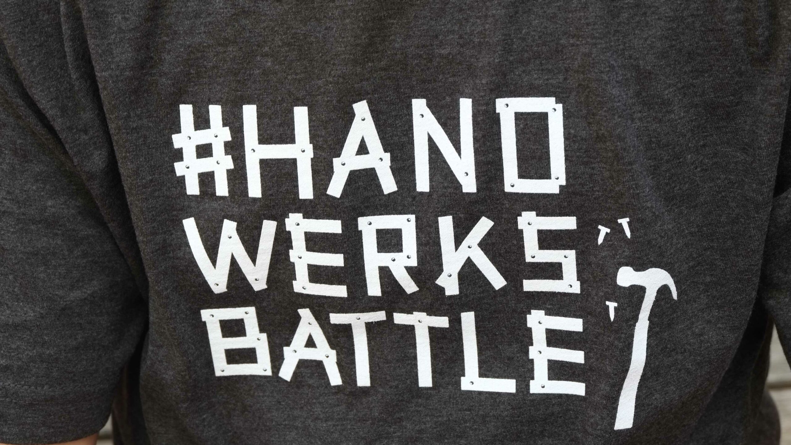Auf diesem Bild sehen Sie einen Pullover mit der Aufschrift „#HANDWERKSBATTLE“.