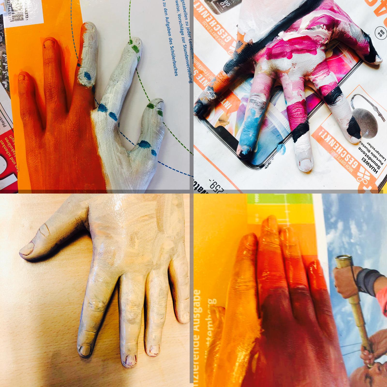 Auf diesem Bild sehen Sie die Kunstprojekte der Klasse 7c. Zu sehen sind beamalte Hände, die auf verschiedenen Unterlagen liegen.