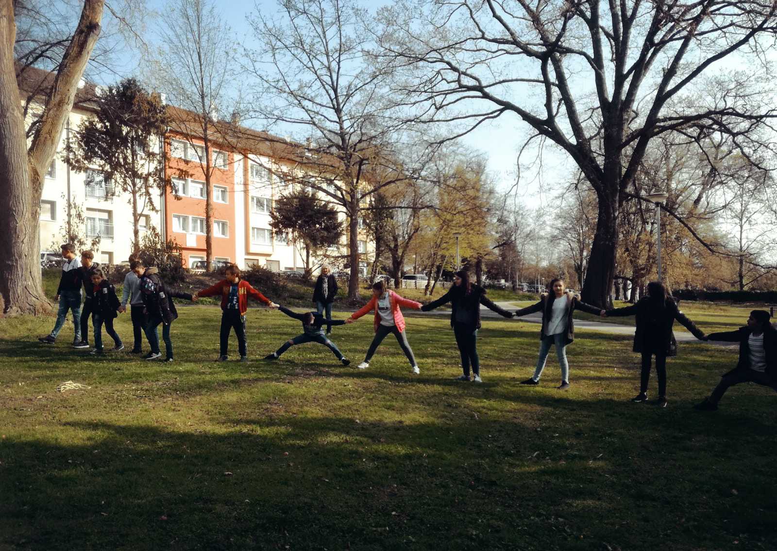 Auf diesem Bild sehen Sie Schülerinnen und Schüler Hand in Hand beim Spielen im Oststadtpark.