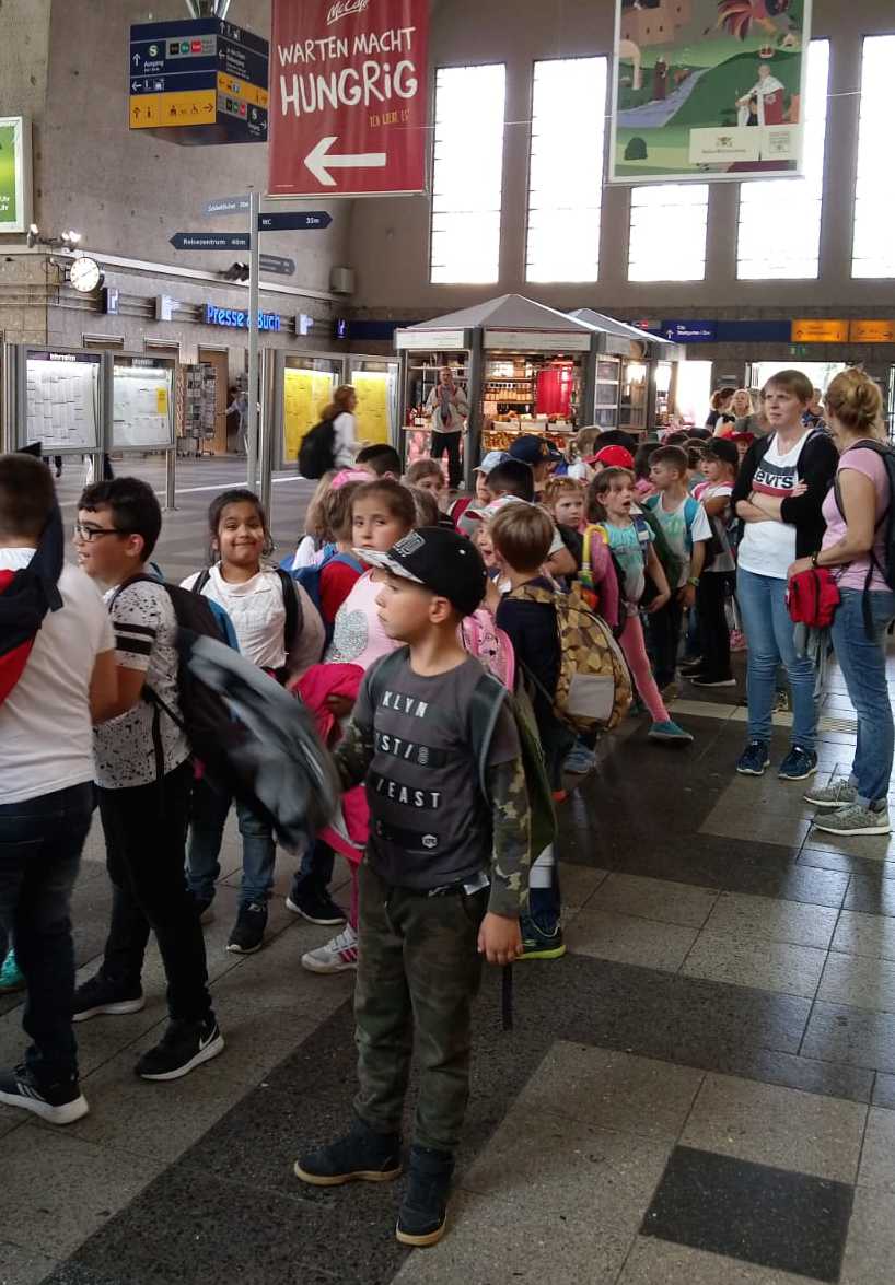 Auf diesem Foto sehen Sie Schülerinnen und Schüler in der Bahnhofshalle.