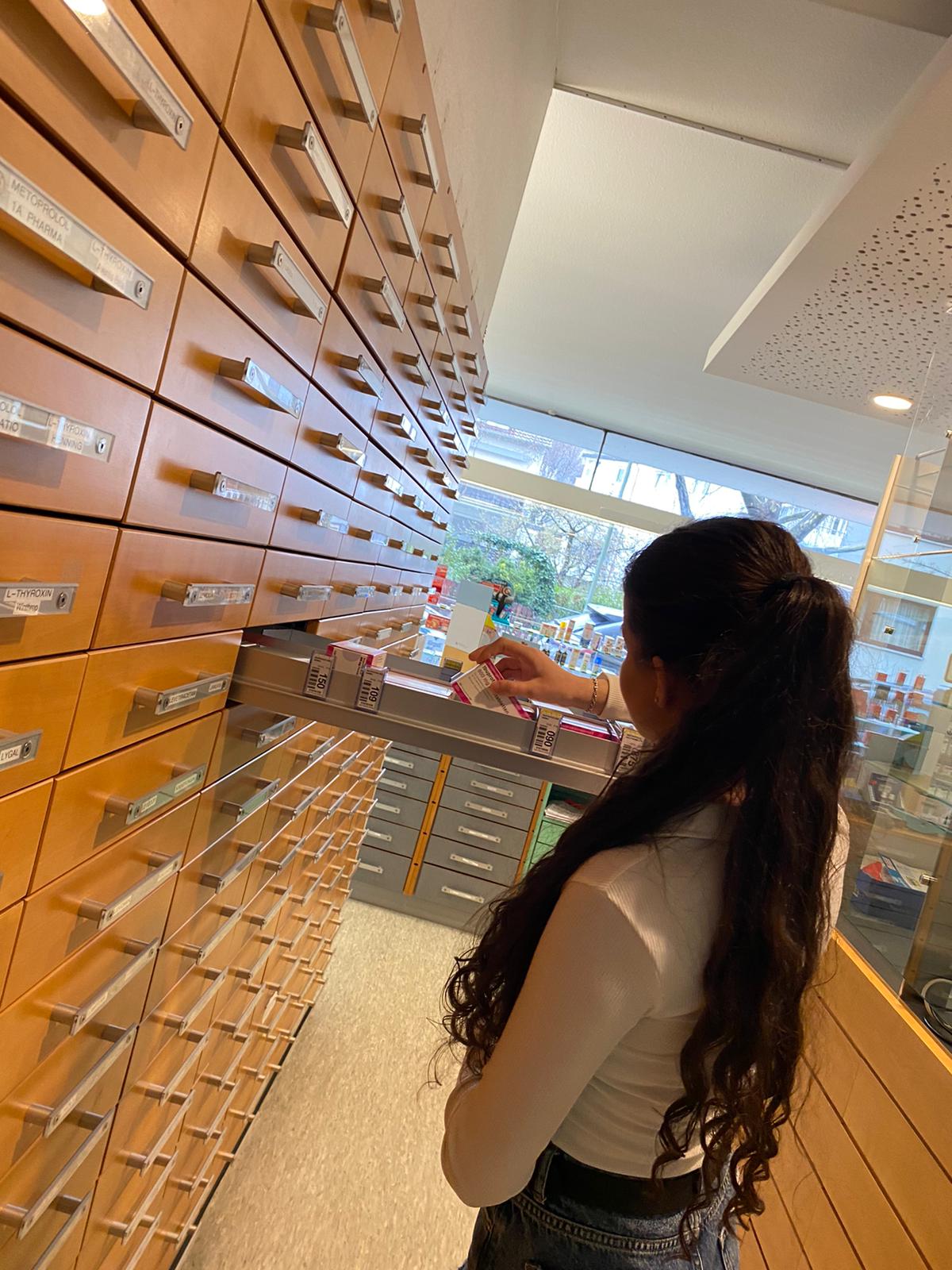 Auf diesem Bild sieht man die Schülerin Samira in einer Apotheke. Sie räumt Medikamente ein.