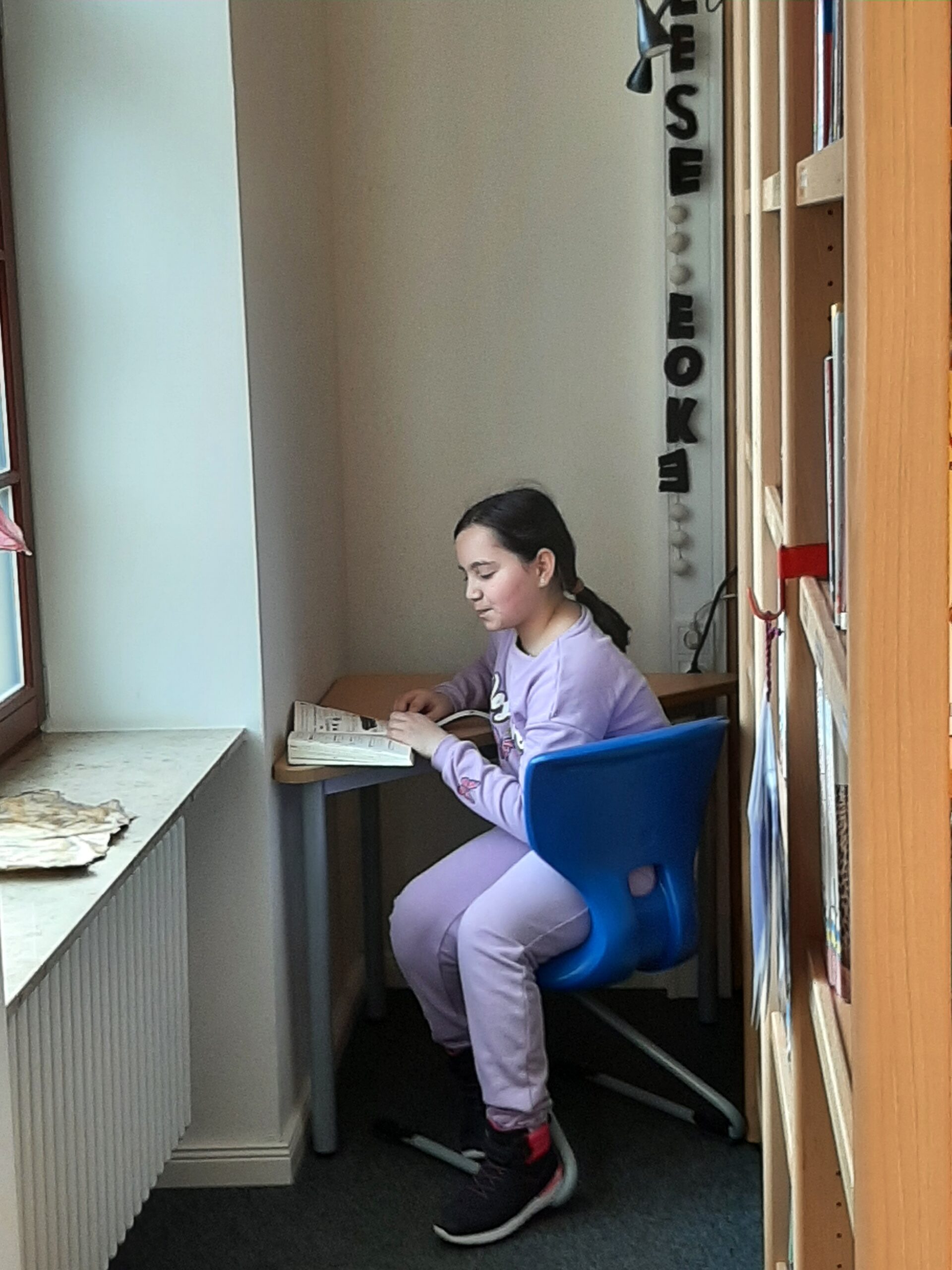 Schülerin liest in in der Schulbibliothek