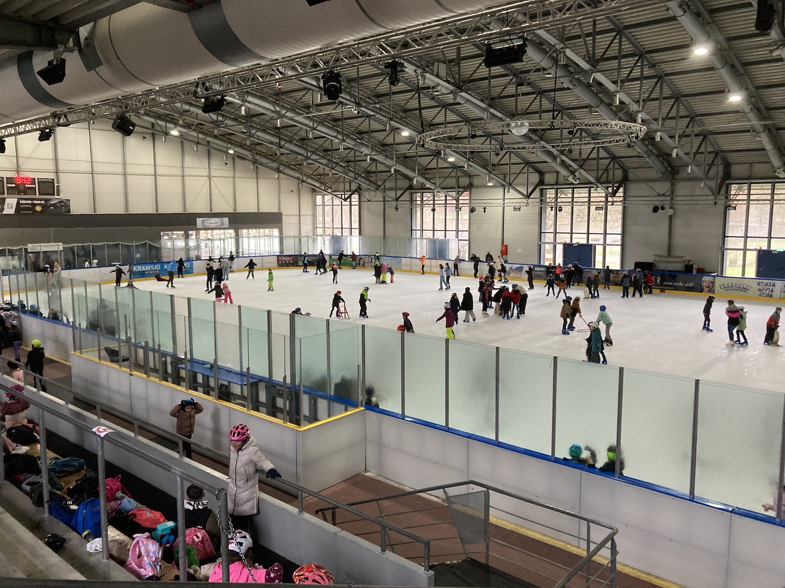 Man sieht Schüler in der Eislaufhalle auf dem Eis Schlittschuh laufen