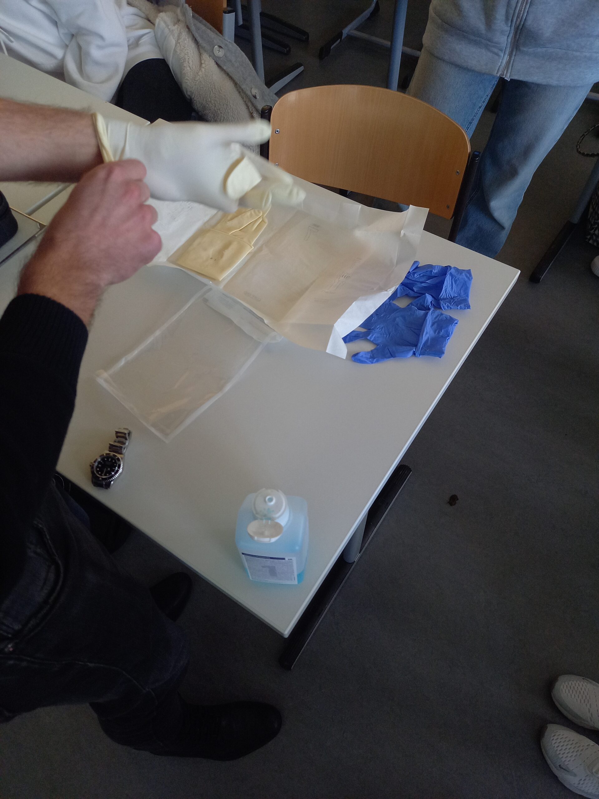 Ein Mann demonstriert wie man sterile Gummihandschuhe anzieht